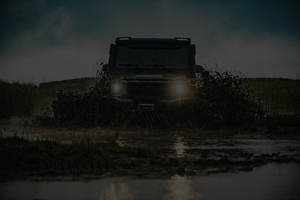 Off Road vehicle head on, splashing through mud.